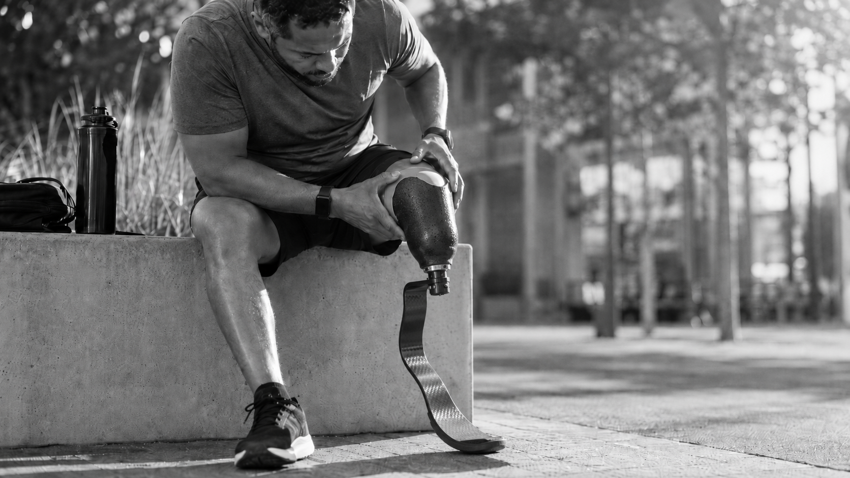 Lower limb amputee adjusting a running blade prosthesis, representing prosthetic socket fit, limb volume variation, heat, and comfort challenges.